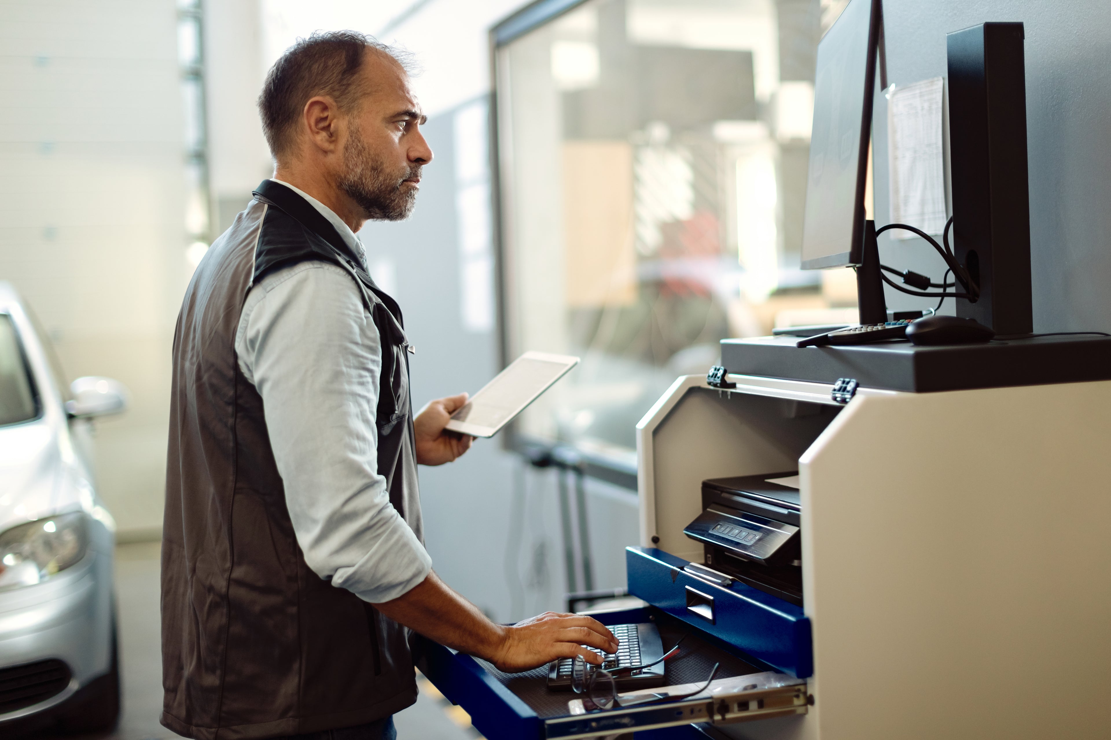 Man using a computer in a car repair shop
